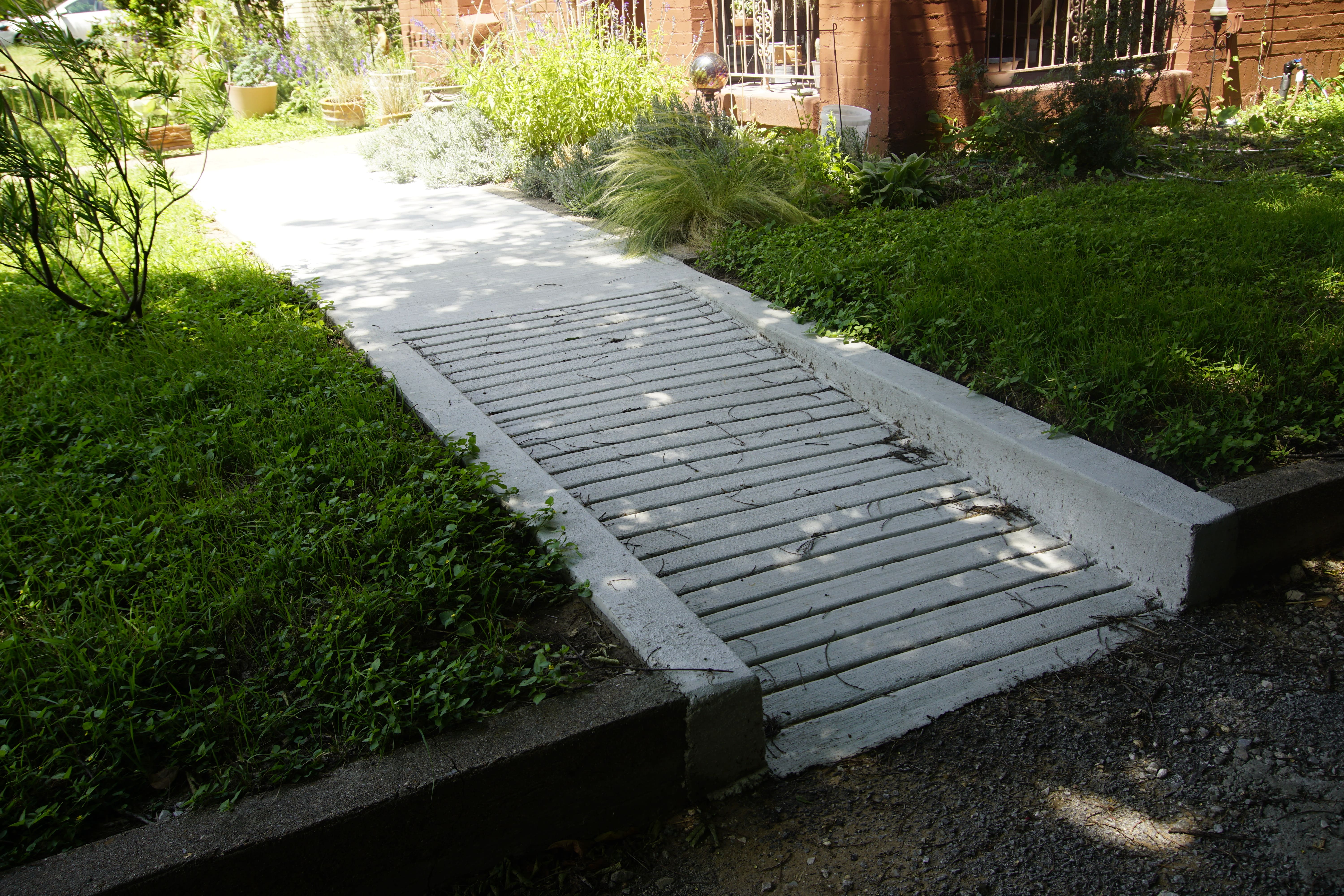 Concrete accessibility ramp with textured non-slip surface in a residential garden walkway